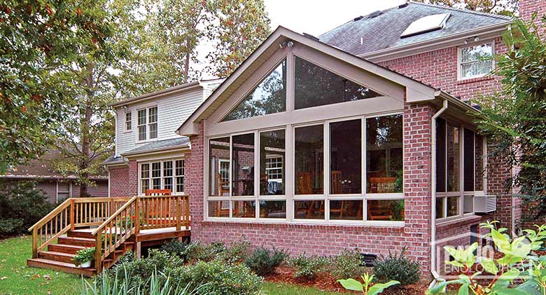 Sandstone four season sunroom with aluminum frame and glass knee wall enclosing an existing covered porch.