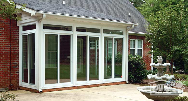White all season sunroom with vinyl frame and transom enclosing an existing covered patio.