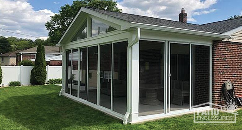 White screen room enclosing existing covered patio with gable roof.