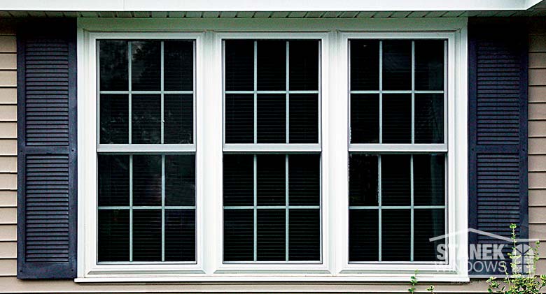 Three double-hung windows mulled together in white with interior colonial grids.