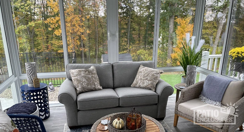 Interior image of a glass porch enclosure with a comfy loveseat decorated for fall.
