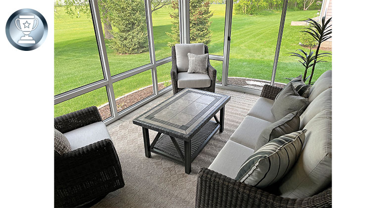 Interior of a screened-in patio with comfortable chairs, sofa, and a coffee table.