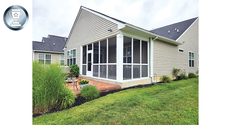 Exterior of a screened-in corner patio with picket railing and storm door. Outdoor patio with table and chairs.