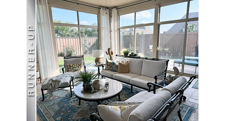 Look up at the exterior of a white three-season patio enclosure with single-sloped roof on a brick home.