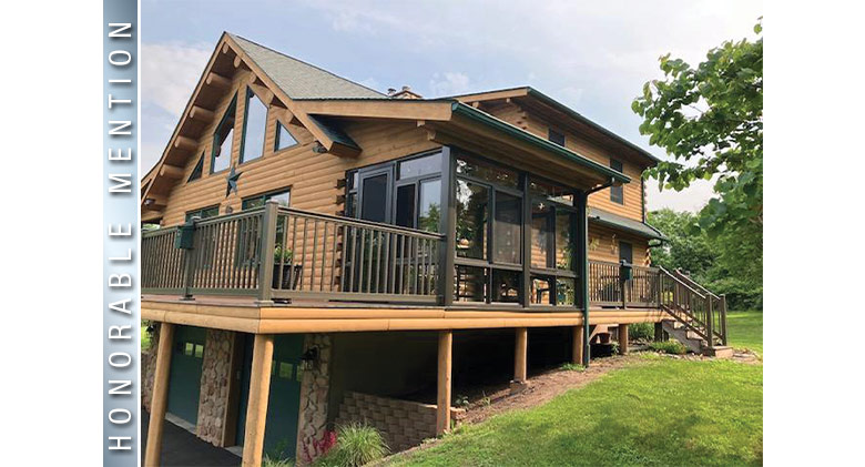 Glass porch enclosure with brown frame on the second level of a log cabin style home, deck on left, stairs on right.