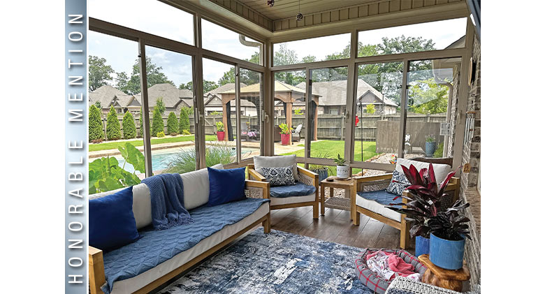 Blue and white cushions on wood furniture in a glass patio enclosure overlooking a pool and outdoor gazebo.