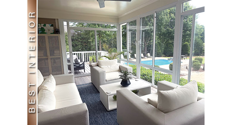Best Interior: Glass three-season sunroom with white upholstered furniture overlooking patio and in-ground pool.