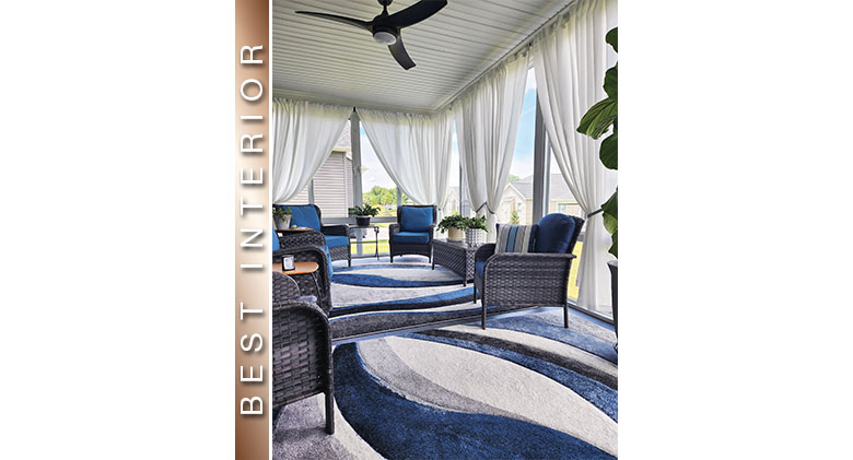 Best Interior: Blue and white swirled rug, blue cushions on wicker, ceiling fan, and white drapes in three-season room.