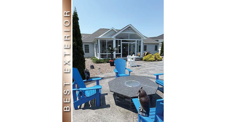 Best Exterior: Bright blue Adirondack chairs and firepit on patio in front of white three-season sunroom with gable roof.
