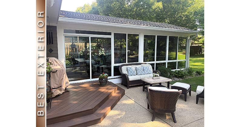 Best Exterior: White three-season patio enclosure behind raised deck and stone patio with wicker furniture.
