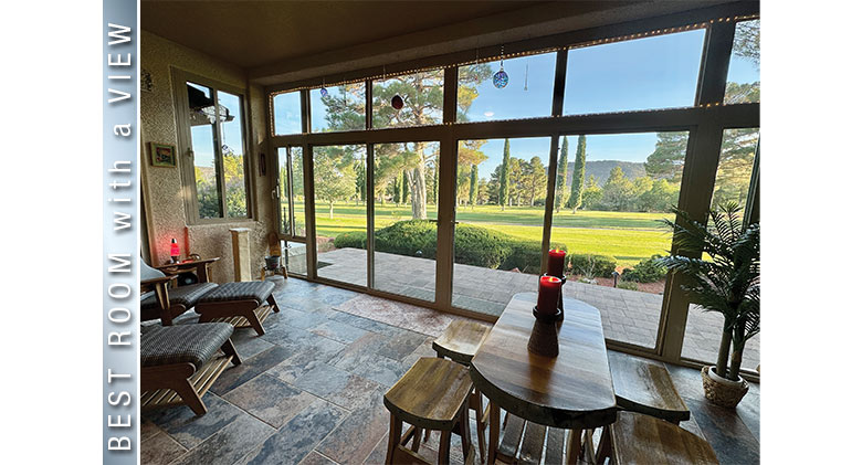 Best Room with a View: Candles lit in interior of patio enclosure with seating, table & chairs, view of large green area.
