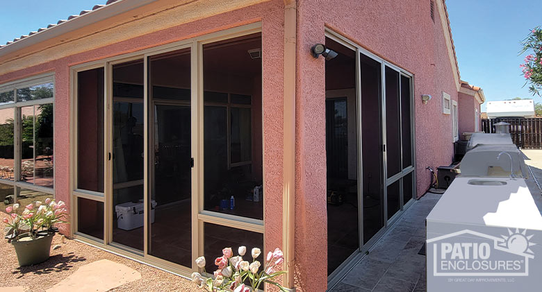 Screened patio enclosure in a pink stucco one-story home in Arizona, potted tulips in front and outdoor kitchen on the side