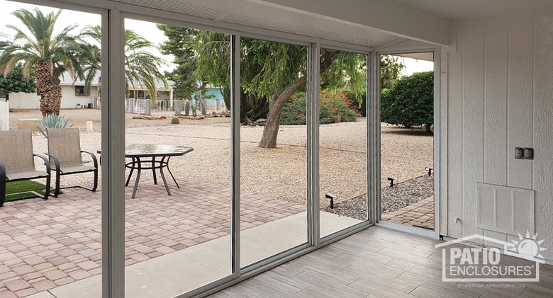 Interior of a screened Arizona room with a view of the yard with a paver patio, various trees and shrubs