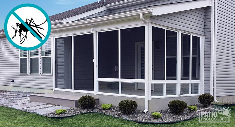 A gray ranch home with a screen room on the back, one step, a walkway, and neat, curved flowerbed with bushes.
