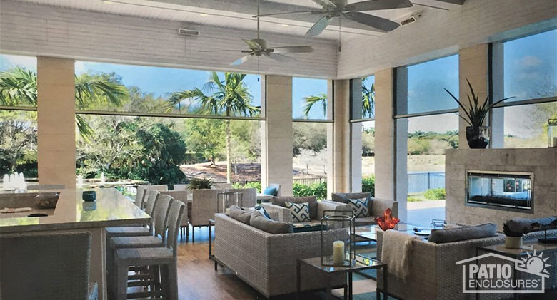 A large, covered patio with white stone columns and black motorized retractable screens partly covering the openings.