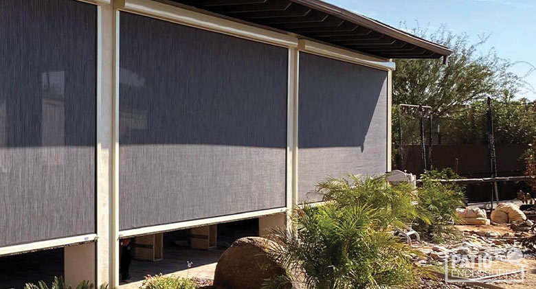A covered patio with opaque brown retractable screens three-quarters of the way down