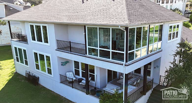 The exterior of a two-story home with a glass corner porch enclosure on the second floor above an open porch area.