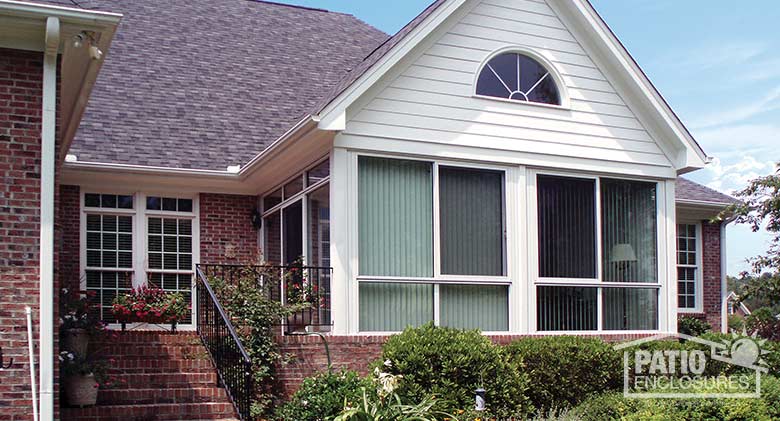 White four season sunroom with aluminum frame and glass knee wall enclosing an existing covered porch.