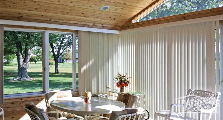 White all season sunroom with aluminum frame, solid knee wall, gable roof and custom woodwork on walls and ceiling.