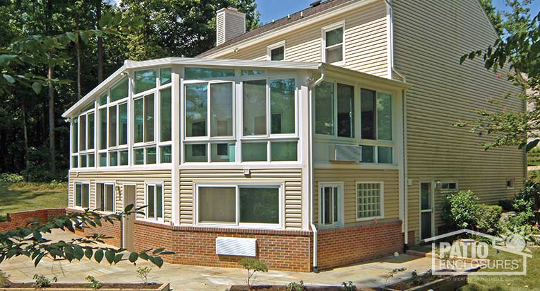 White four season sunroom with vinyl frame, glass knee wall and gable roof with glass roof panels.