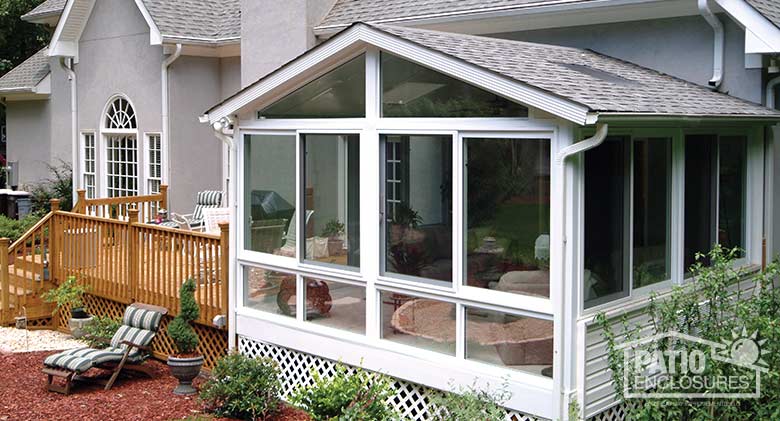 White four season sunroom with vinyl frame, glass knee wall and gable roof with glass roof panels.