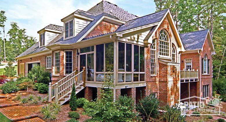 Sandstone four season sunroom with vinyl frame and glass knee wall enclosing an existing covered porch.