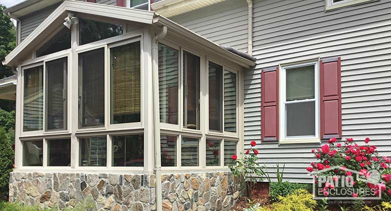 Sandstone four season sunroom with vinyl frame, glass knee wall and gable roof.