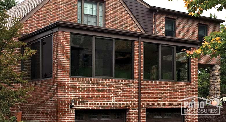 Bronze all season sunroom with aluminum frame enclosing an existing over-the-garage porch.