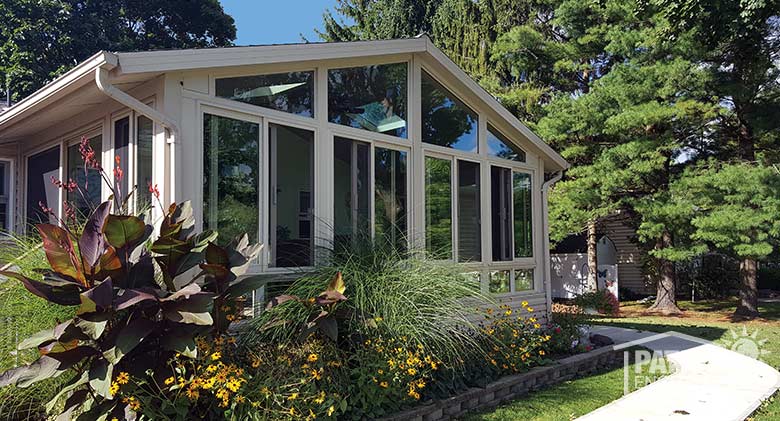 Sandstone all season sunroom with vinyl frame and gable roof.