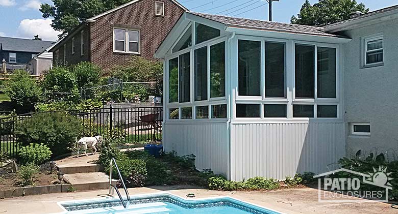 White all season sunroom with vinyl frame and shingled gable roof.