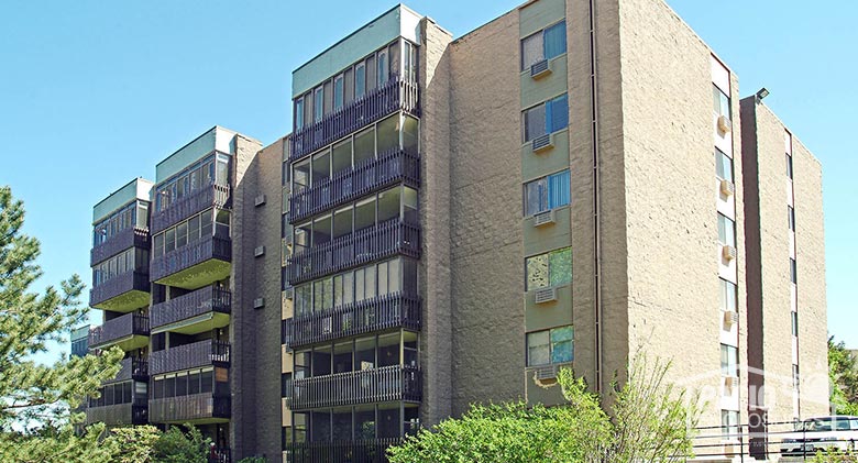 Screen rooms in bronze with picket railing systems enclosing existing covered balconies at multi-story condominium.