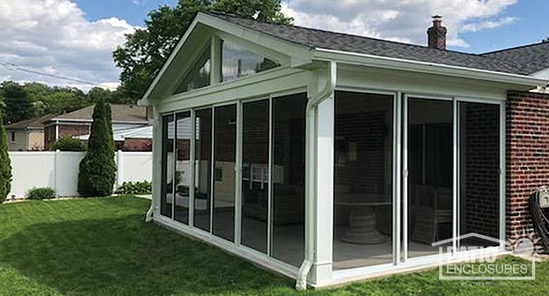 Screen room in white enclosing an existing covered patio with gable roof.