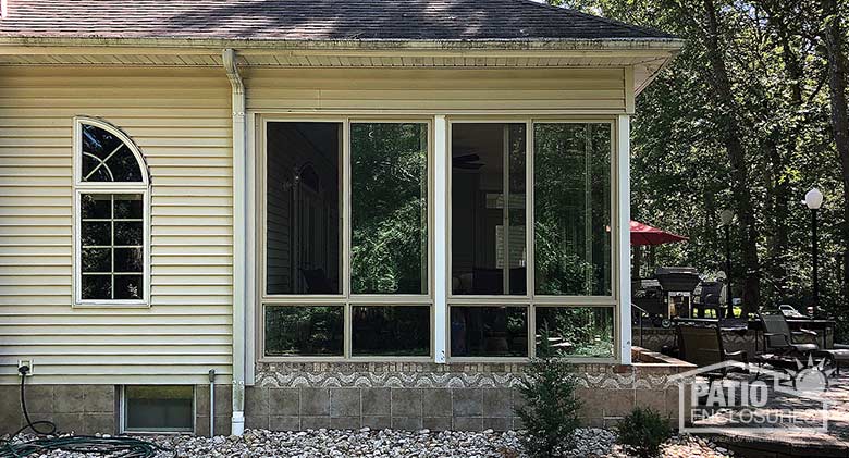 Elite three season room in sandstone and glass knee wall enclosing an existing covered porch.