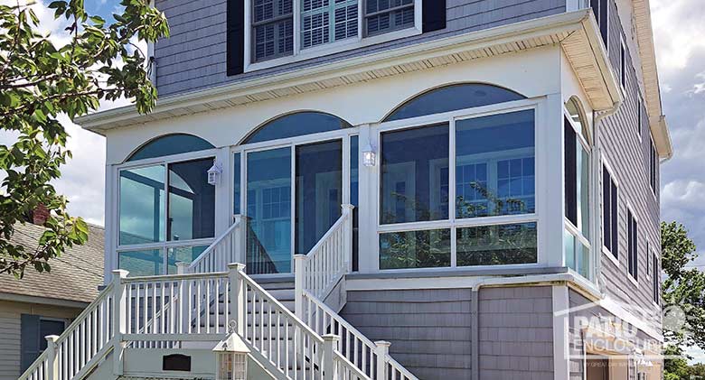 Elite three season room in white with glass knee wall enclosing an existing front porch.