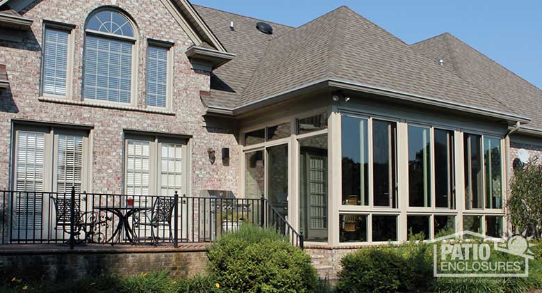 Three season room in sandstone with glass knee wall enclosing an existing covered porch.