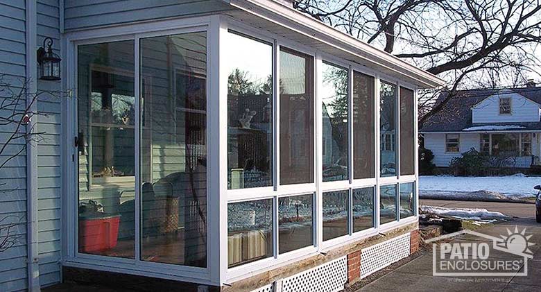 Three season room in white with glass knee wall enclosing an existing wraparound porch.