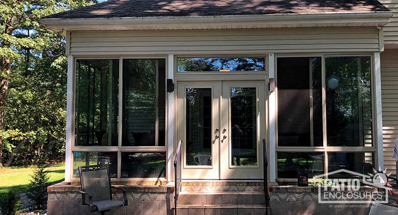 Elite three season room in sandstone with glass knee wall enclosing an existing covered porch.