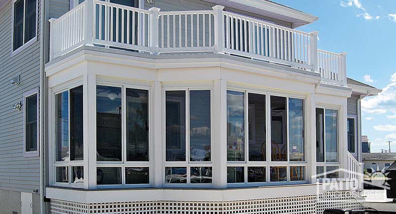 Elite three season room in sandstone with glass knee wall enclosing an existing covered porch.