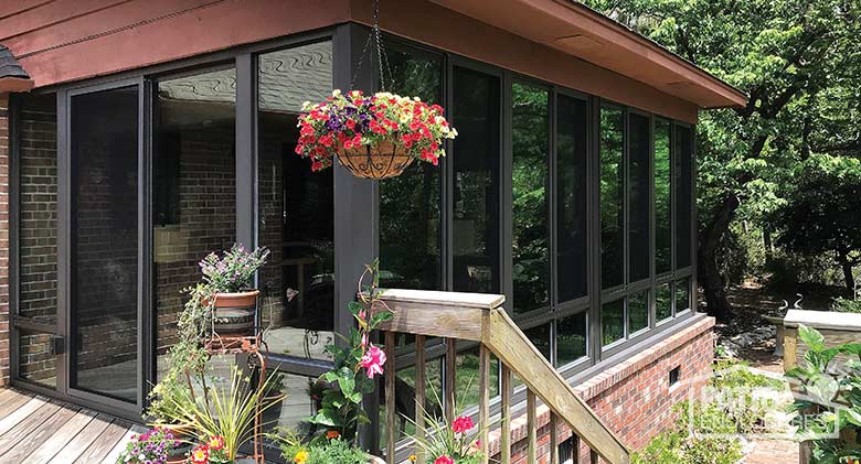 Three season room in bronze with insulated glass and glass knee wall enclosing an existing screen room.