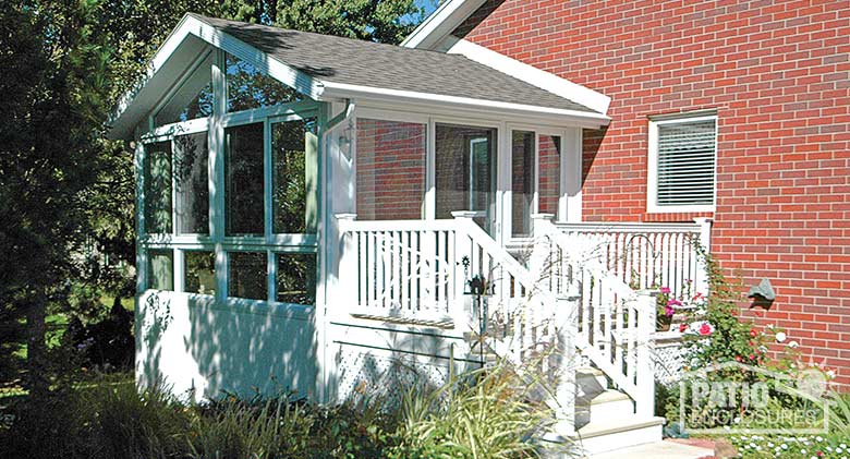 White four season sunroom with vinyl frame, glass knee walls and shingled gable roof.