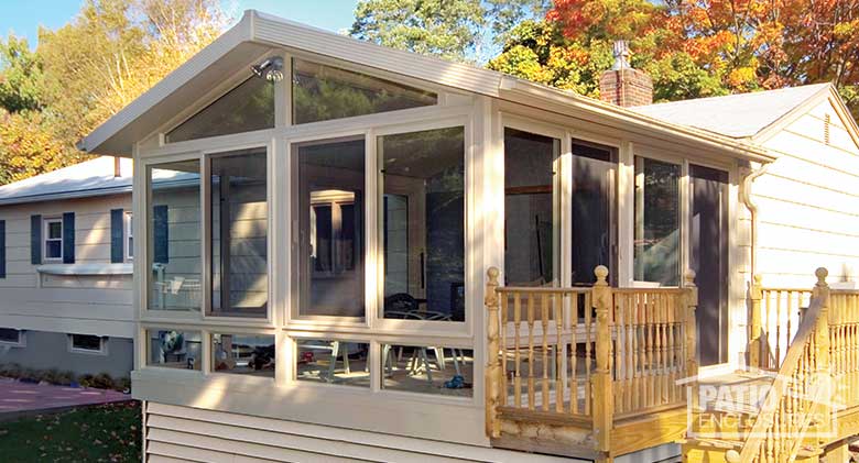 Sandstone four season room with vinyl frame, glass knee walls and gable roof.