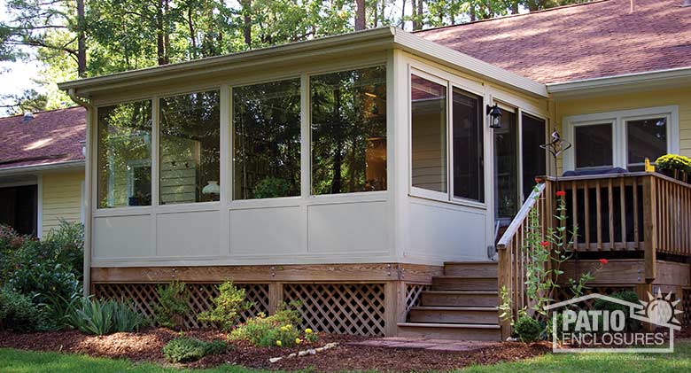Sandstone four season sunroom with vinyl frame, solid knee wall and single-slope roof.