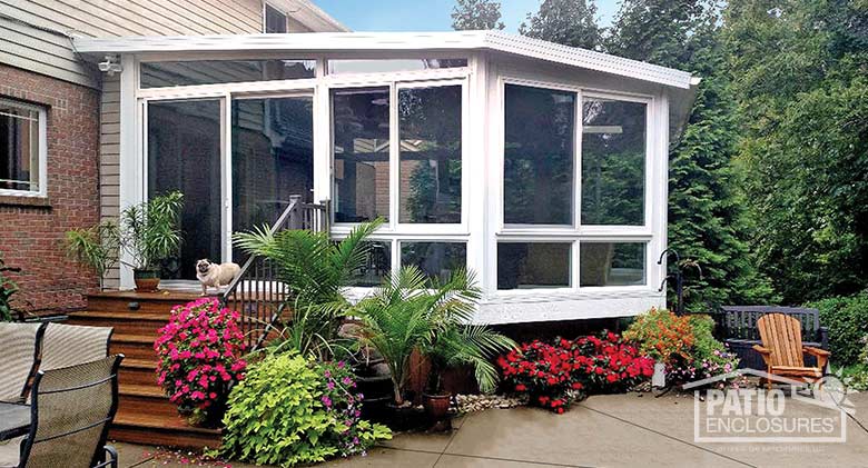 White four season sunroom in an unusual shape with vinyl frame, glass knee walls and single-slope roof.