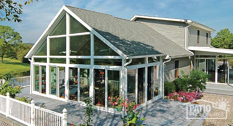 White four season sunroom with vinyl frame, transoms and shingled gable roof.