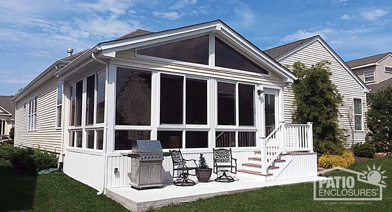 White four season sunroom with vinyl frame, glass knee walls and shingled gable roof.