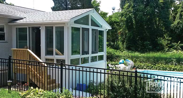 White four season sunroom with vinyl frame, glass knee walls and shingled gable roof.