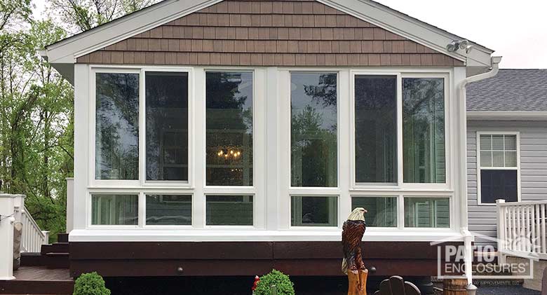 White four season sunroom with vinyl frame and glass knee wall enclosing an existing covered porch.