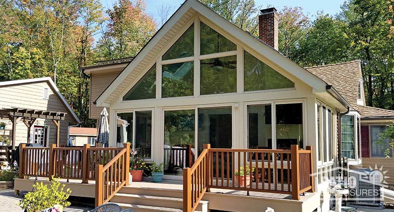 Sandstone four season sunroom with vinyl frame, glass knee walls and shingled gable roof.