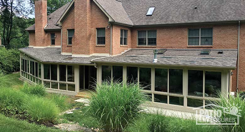 Two sandstone four season rooms with vinyl frames, glass knee walls and shingled, single-sloped roofs.