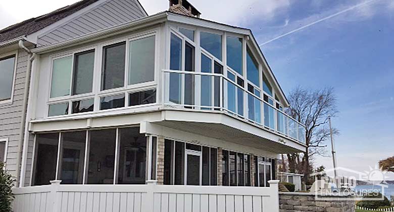 White four season sunroom with vinyl frame and glass knee wall enclosing an existing covered porch.